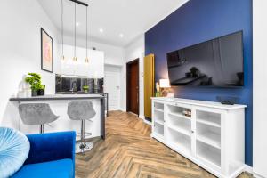 Il comprend un salon doté d'une télévision et d'un mur bleu. dans l'établissement EASY RENT Apartments - Chopina 32, Centrum, 24h Check-in, à Lublin 7 autres photos