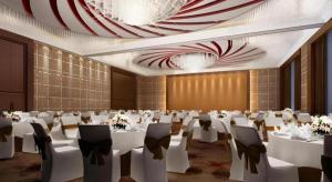 une salle de banquet avec des tables et des chaises blanches et un lustre dans l'établissement Grand Skylight International Hotel Guiyang, à Guiyang