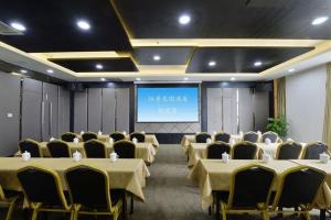 a conference room with tables and chairs and a projection screen at Xian Yi Jing Garden Hotel in Xi'an