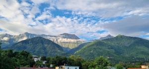 a view of a mountain range with clouds in the sky at Peace Yard in Dharmsāla