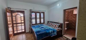 a bedroom with a bed with a blue comforter at Peace Yard in Dharmsāla