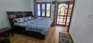 a bedroom with a bed with a blue comforter at Peace Yard in Dharmsāla +5 photos