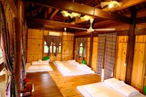 a room with white beds in a room with wooden walls at Nhà sàn cộng dồng - The Valley Farm in Hữu Lũng