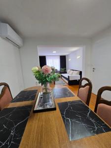 a dining room table with a vase of flowers on it at Apartman SAN in Sarajevo +11 photos