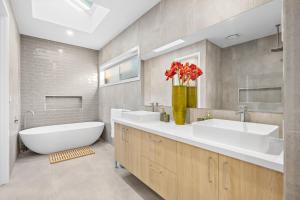 Un baño con dos lavabos y una bañera y un jarrón de flores. en Hathaway Haven, en Alfredton