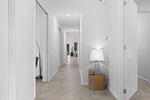 un pasillo con paredes blancas y una lámpara en una mesa en Hathaway Haven, en Alfredton