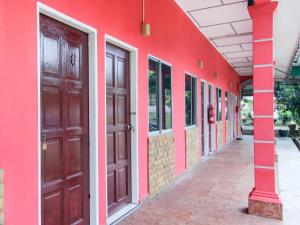 a red building with two brown doors on the side at OYO 89684 Mawaddah Inn Stay in Kampong Bukit Kechil