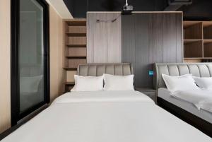 two beds with white pillows in a room at Shanpanyisu Hotel in Chongqing +1 photo