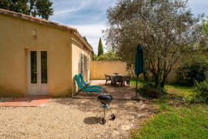 un patio con mesa, silla y sombrilla en Maisonnette Provençale, en Le Thor