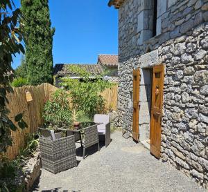 a stone house with a table and a fence at Chambre d'hôtes et de charme "Au Clos des Ammonites chez Ange&Sébastien " in Labeaume