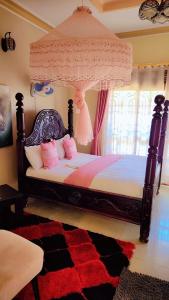 a bedroom with a canopy bed with pink pillows at Greg j & m suites in Kira