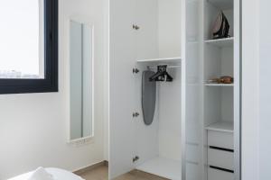un placard blanc avec un miroir et un parapluie dans l'établissement Jas Living - Chic Apts & Balconies in Larnaca, à Larnaka 128 autres photos