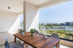 une salle à manger avec une table et des chaises en bois ainsi qu'une grande fenêtre dans l'établissement Jas Living - Chic Apts & Balconies in Larnaca, à Larnaka