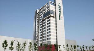 a tall white building with trees in front of it at GreenTree Inn Tianjin JinNan ShuangLin Metro Station Express Hotel in Tianjin