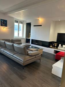 a living room with a leather couch and a television at Maison de Maître in Tramelan