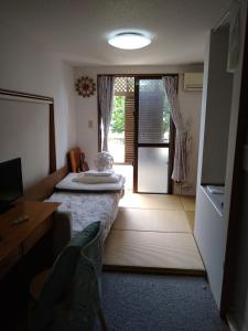 a room with a bed with a table and a window at Minshuku Zabaru in Ishigaki Island