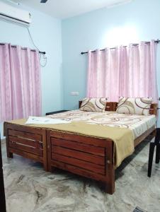 バルカラにあるShalimar Residencyのピンクのカーテンがかかった部屋にある大きなベッド