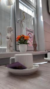Ein Teller auf einem Tisch, dazu eine Tasse und eine Vase mit Blumen. in der Unterkunft Уютная 1 комнатная квартира в самом центре Шымкента in Zhezdi