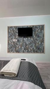 ein Bett in einem Zimmer mit einem Gemälde an der Wand in der Unterkunft Уютная 1 комнатная квартира в самом центре Шымкента in Zhezdi