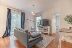 un soggiorno con un divano e una TV di Le Rev'touch T2 avec balcon & parking proche Airbus a Tolosa