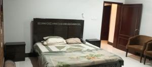 een slaapkamer met een bed en een stoel bij RESIDENCY GUEST HOUSE University Town Peshawer in Peshawar