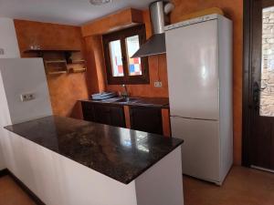 Il comprend une cuisine équipée d'un réfrigérateur blanc et d'un comptoir noir. dans l'établissement Casa Paulonia, à Las Negras