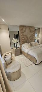 ein Schlafzimmer mit 2 Betten, einem Stuhl und Blumen in der Unterkunft Villa De Luna in Avondale, Lomagundi Road in Tudeley