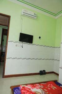 Ein Zimmer mit einer weiß gefliesten Wand und einem Fernseher an der Wand in der Unterkunft Nhà Nghỉ Mỹ Linh - Quảng Ngãi in Mỹ Lộc