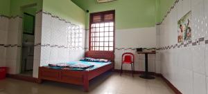 ein Zimmer mit einem Bett und einem roten Stuhl darin in der Unterkunft Nhà Nghỉ Mỹ Linh - Quảng Ngãi in Mỹ Lộc