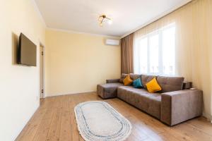 ein Wohnzimmer mit Sofa und Fernseher in der Unterkunft Просторная квартира с балконом в ЖК Атлант in Almaty