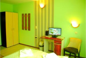 Cette chambre verte comprend un lit et un bureau avec un ordinateur. dans l'établissement Панорама- стаи за гости, à Svishtov