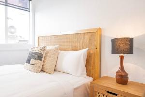a bed with pillows and a lamp on a night stand at 1950 Serenity - Classic Hobart Escape near CBD in West Hobart