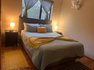 a bedroom with a bed with two lamps and a window at Erdvarkie at Kruger, Marloth Park in Marloth Park +4 photos