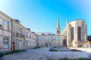 a large building with a church in the background at Logis de la Trinité - Appt climatisé in Mauléon