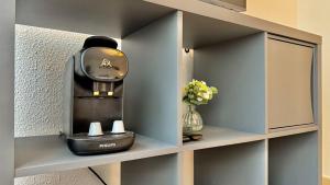 Una cafetera en un estante junto a un jarrón de flores en Flowers Studio, en Saint-Julien-en-Genevois