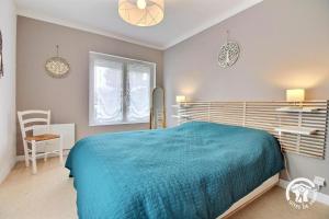 Un dormitorio con una cama azul y una ventana. en La petite godaille, en Auray