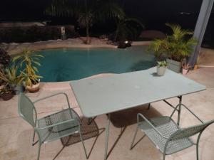 a table and chairs next to a swimming pool at Le lagon de Stella in Saint-Leu