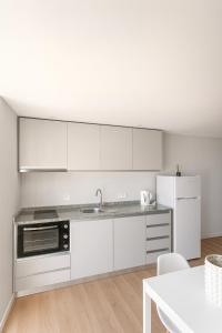 a kitchen with white cabinets and a sink and a refrigerator at Douro Vila 10 - Best View in Town in Bandeira