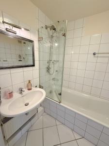 Un baño blanco con lavabo y ducha. en Frisch renoviertes FH Südblick am Meer in Breege, Meerblick von allen drei Etagen, Terrasse, Balkon, Sauna und Parkplatz, en Breege