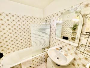 a bathroom with a sink and a mirror and a tub at Le Chaleureux in Marignier
