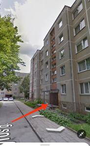 ein Gebäude mit einem orangefarbenen Pfeil neben einer Straße in der Unterkunft Vieno kambario butas Šiauliuose in Šiauliai