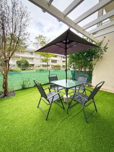 a table and chairs with an umbrella on a lawn at L'Acacia in Aytré