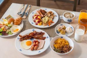 a table with plates of breakfast food on it at Montien Hotel Surawong Bangkok in Bangkok