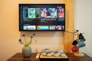 Ein Fernseher an der Wand, daneben ein Tisch mit einer Vase in der Unterkunft otani 201 in Osaka