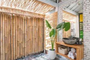 a bathroom with a wooden wall with a sink and a plant at Sanctuary Villas in Ubud +35 photos