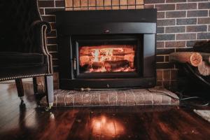 a fireplace in a living room with a brick wall at Lindsay House Guest House in Armidale