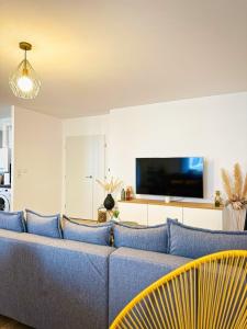 a living room with a blue couch and a tv at L'Atelier des Arts in La Rochelle