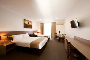 Habitación de hotel con cama, escritorio y mesa. en Adelong Motel en Narrabri