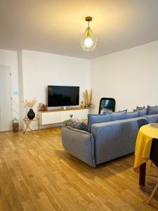 a living room with a blue couch and a tv at L'Atelier des Arts in La Rochelle