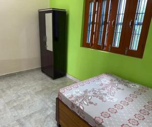 Un dormitorio con una cama y una pared verde. en Stay Enjoy, en Jāmb